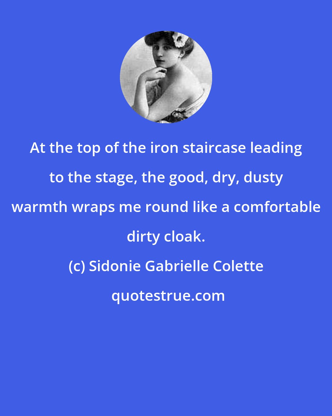 Sidonie Gabrielle Colette: At the top of the iron staircase leading to the stage, the good, dry, dusty warmth wraps me round like a comfortable dirty cloak.